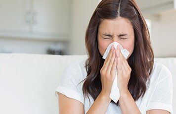 Woman Sneezing in a Tissue — Allergy Clinic in Idaho Falls, ID