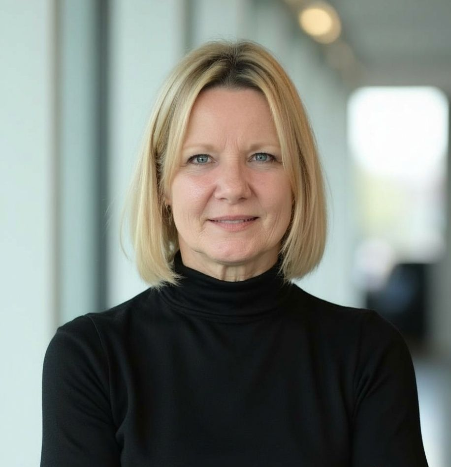 Blonde woman in a blazer smiling at the camera against a white background.