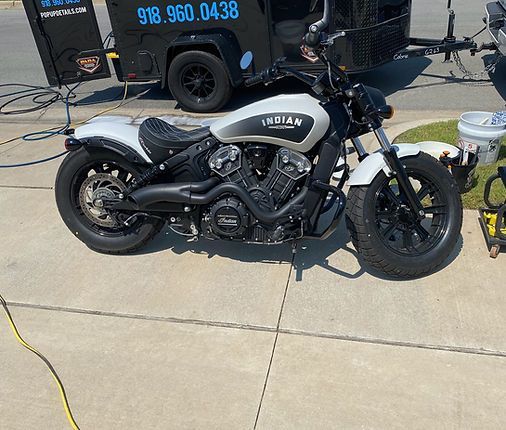 A motorcycle is parked on the side of the road next to a trailer.