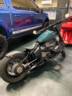 A motorcycle is parked in a garage next to a truck.
