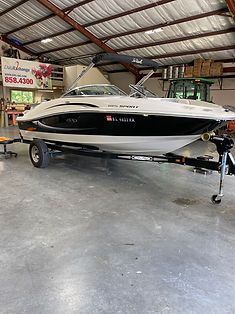 A boat is parked in a garage with a trailer attached to it.