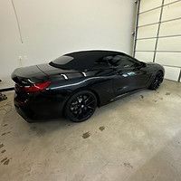 A black convertible is parked in a garage next to a garage door.