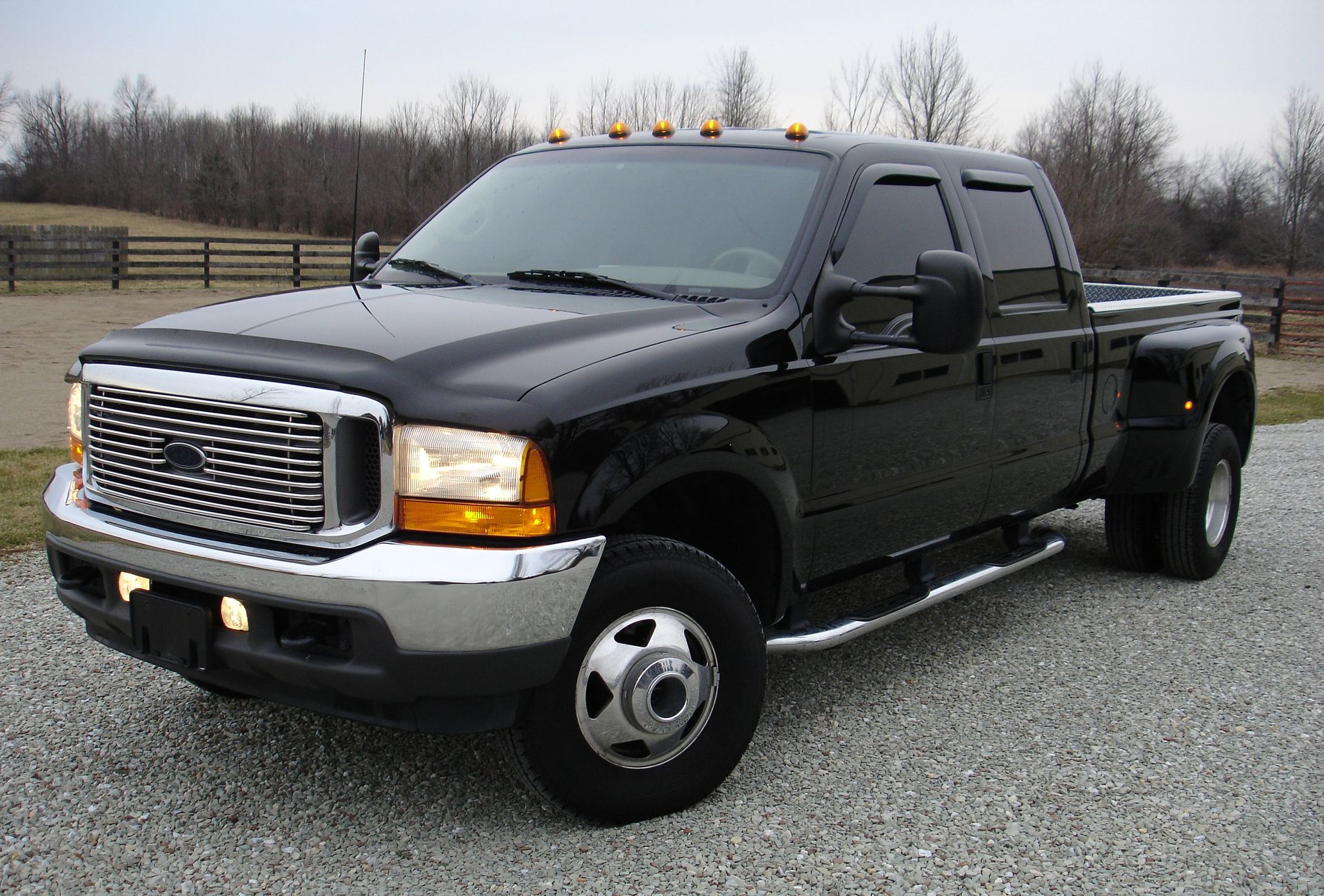 A black ford truck is parked in a gravel lot