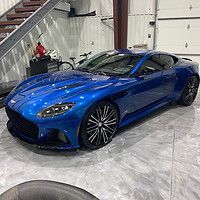 A blue sports car is parked in a garage next to a staircase.