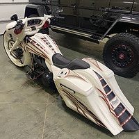 A white motorcycle is parked next to a black jeep in a garage.