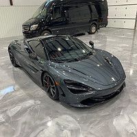 A mclaren 720s is parked in a garage next to a van.