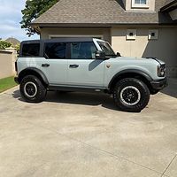 A ford bronco is parked in a driveway in front of a house.