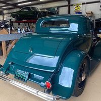 A green vintage car is parked in a garage.
