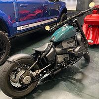 A motorcycle is parked next to a blue truck in a garage.