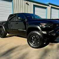 A black truck is parked in front of a building.