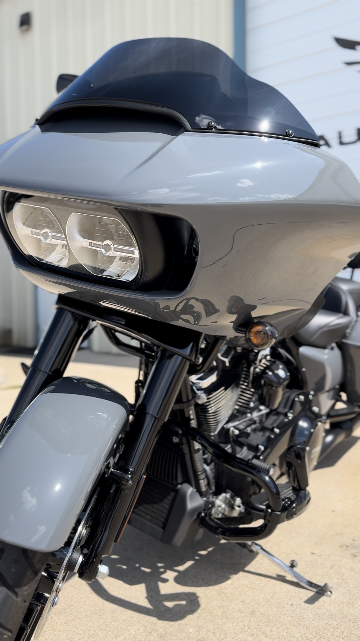 A gray Harley-Davidson Road Glide motorcycle parked outside, with a fairing, two headlamps, and a black windshield.