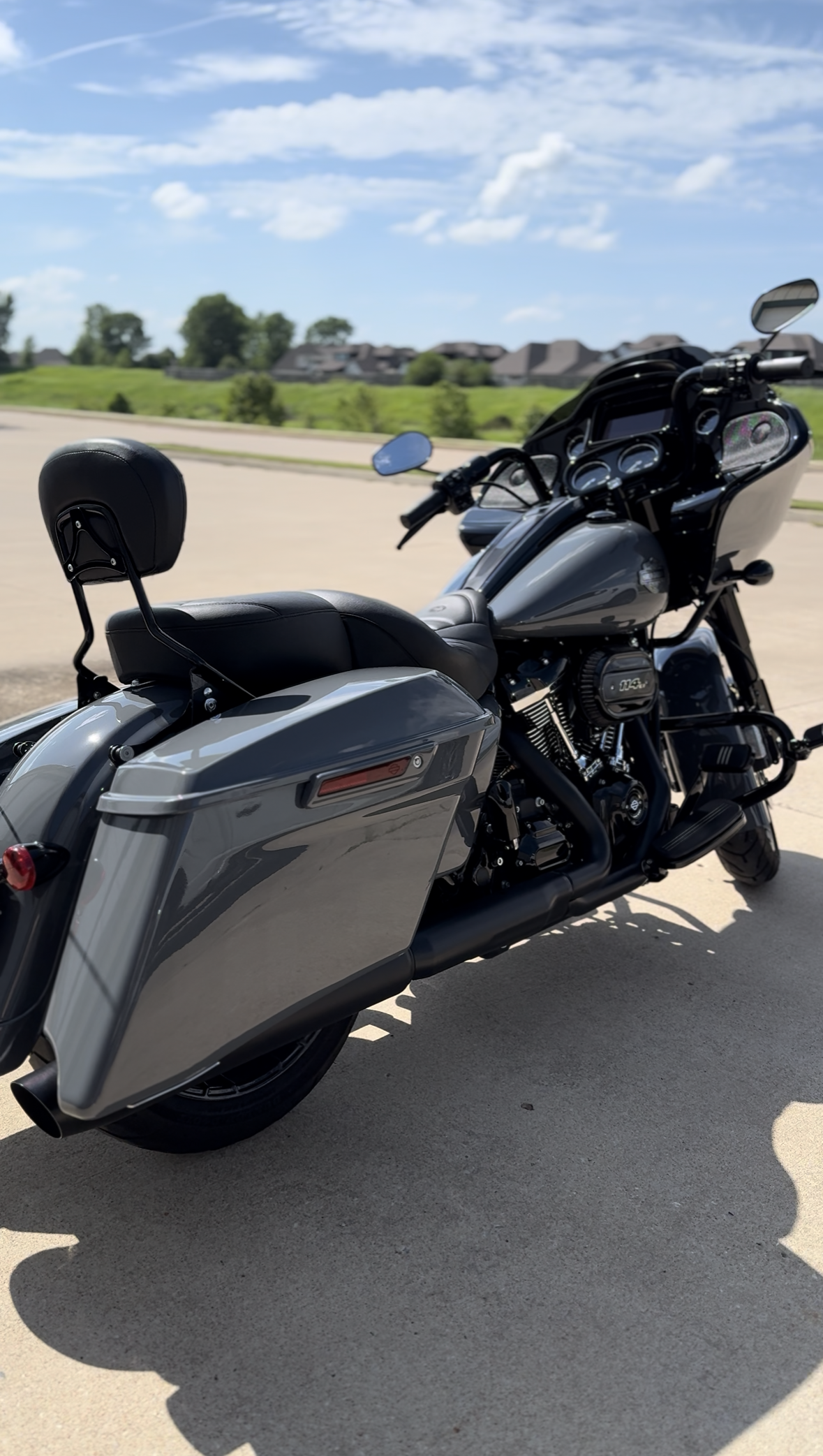 Gray Harley-Davidson motorcycle parked outdoors on a sunny day. It has saddlebags and a backrest.