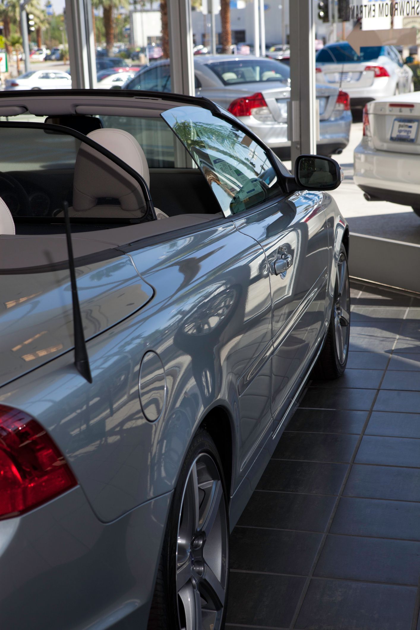 A silver convertible car is parked in a showroom.
