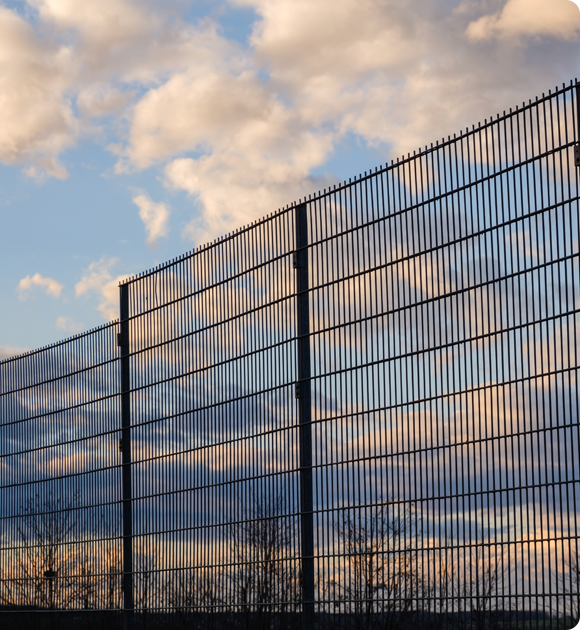 A fence with a cloudy sky in the background