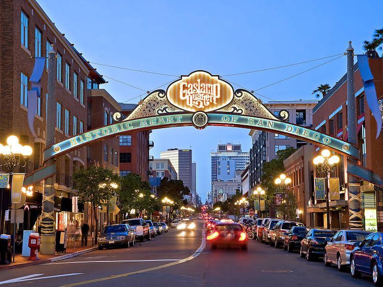 A car is driving down a city street under a neon sign.