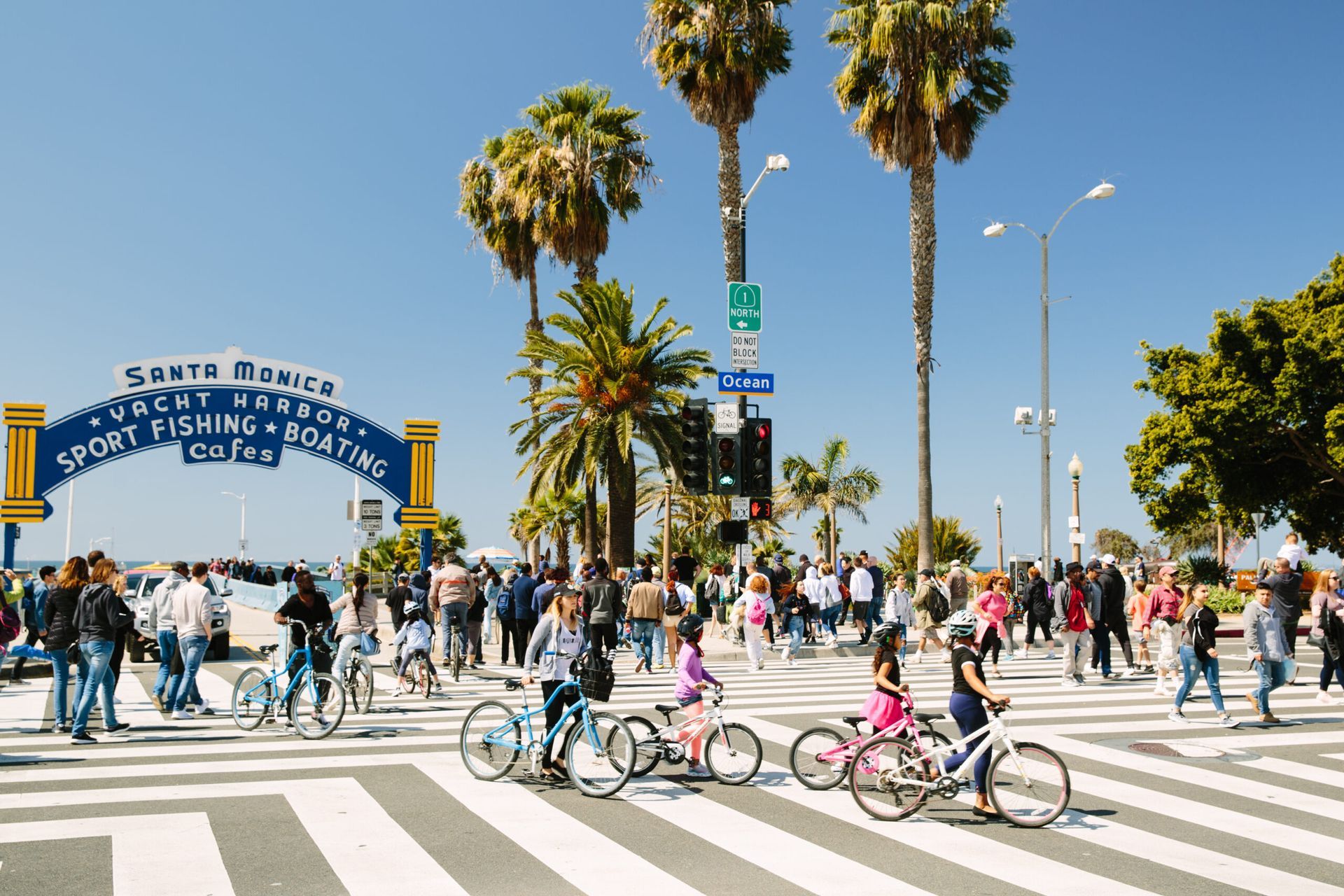 A group of people are crossing a street in front of a sign that says santa monica