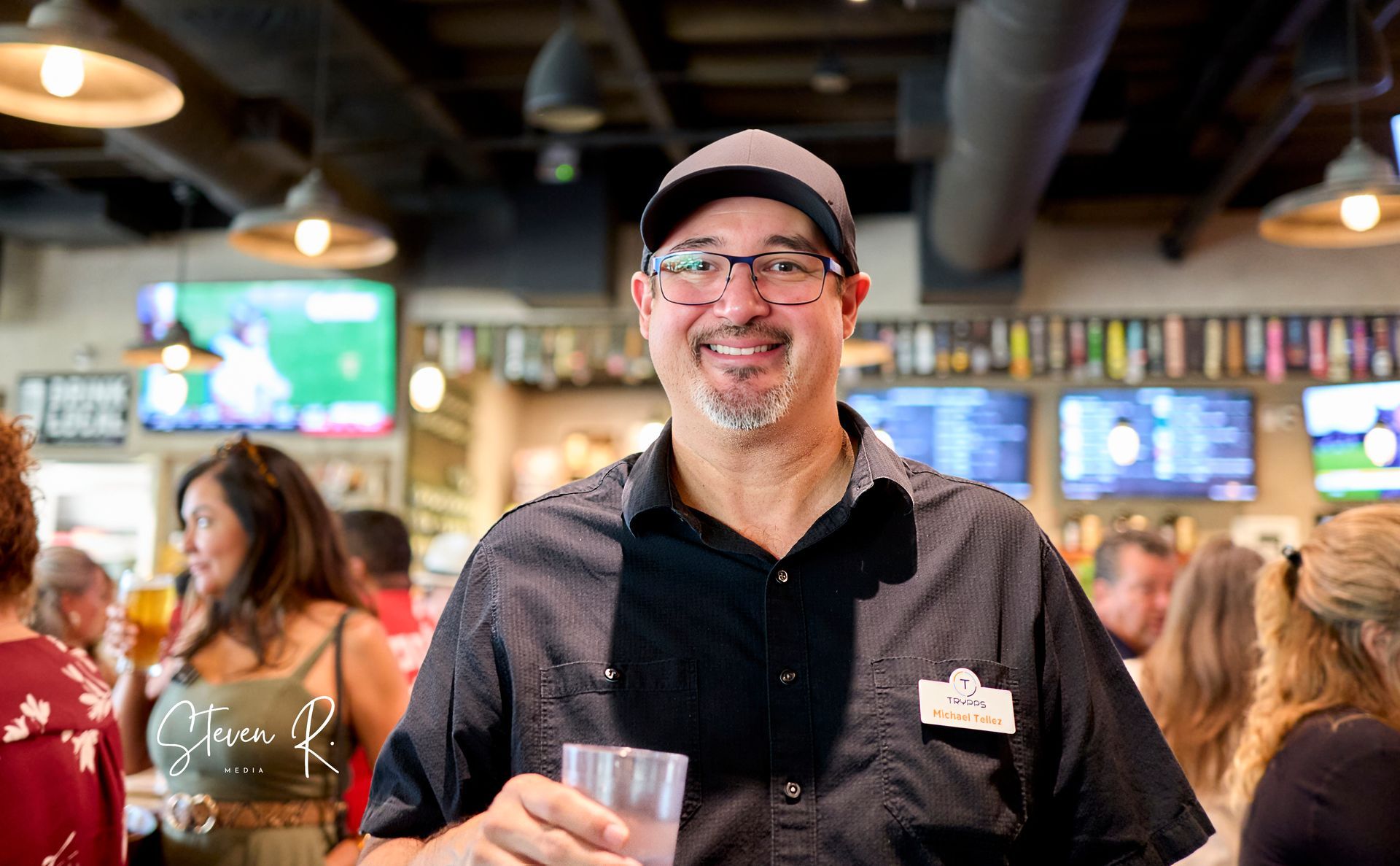 A man is holding a glass of beer in a restaurant.