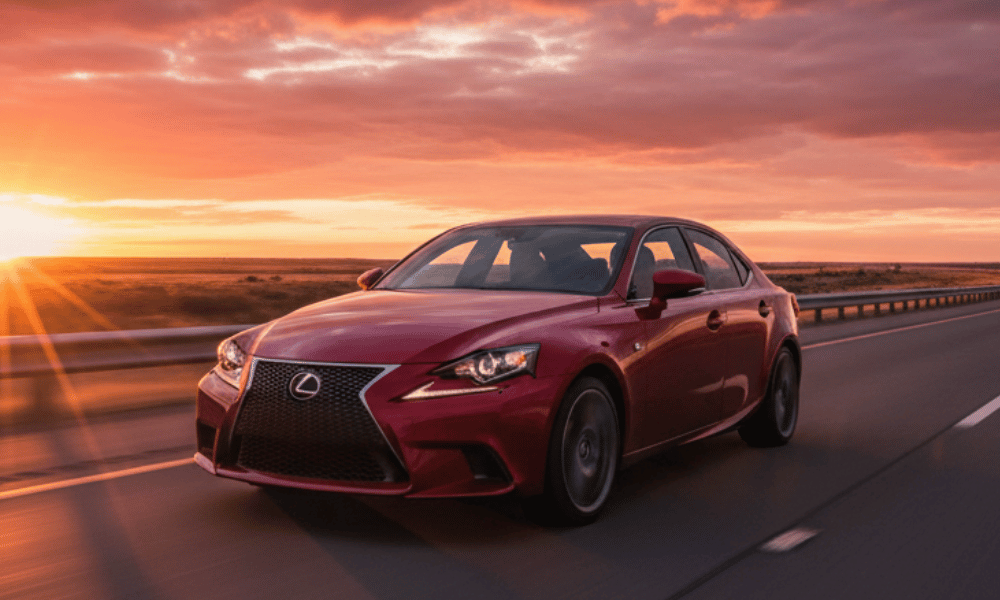 Red Lexus sedan driving on highway at sunset