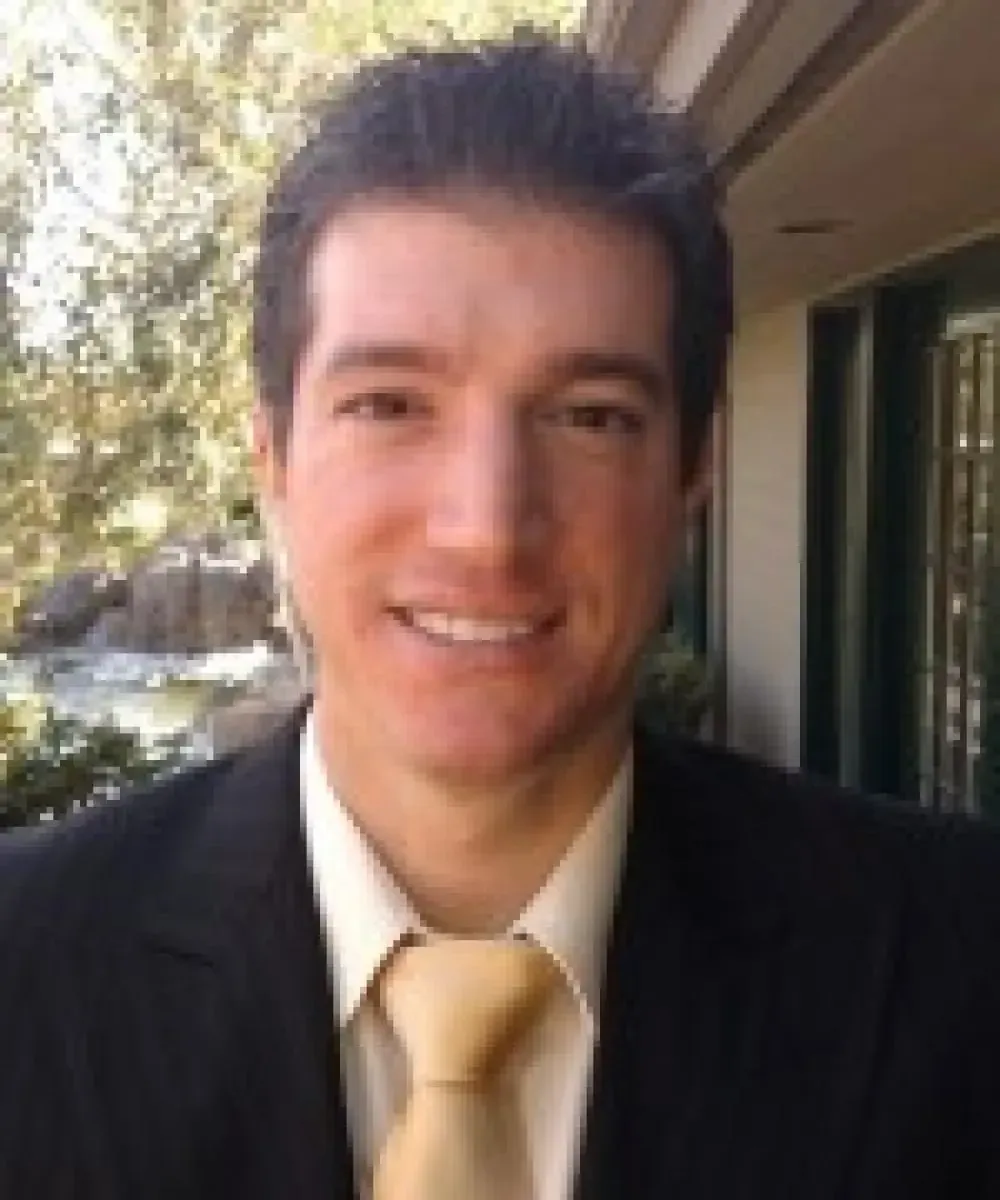 A man in a suit and tie is smiling for the camera