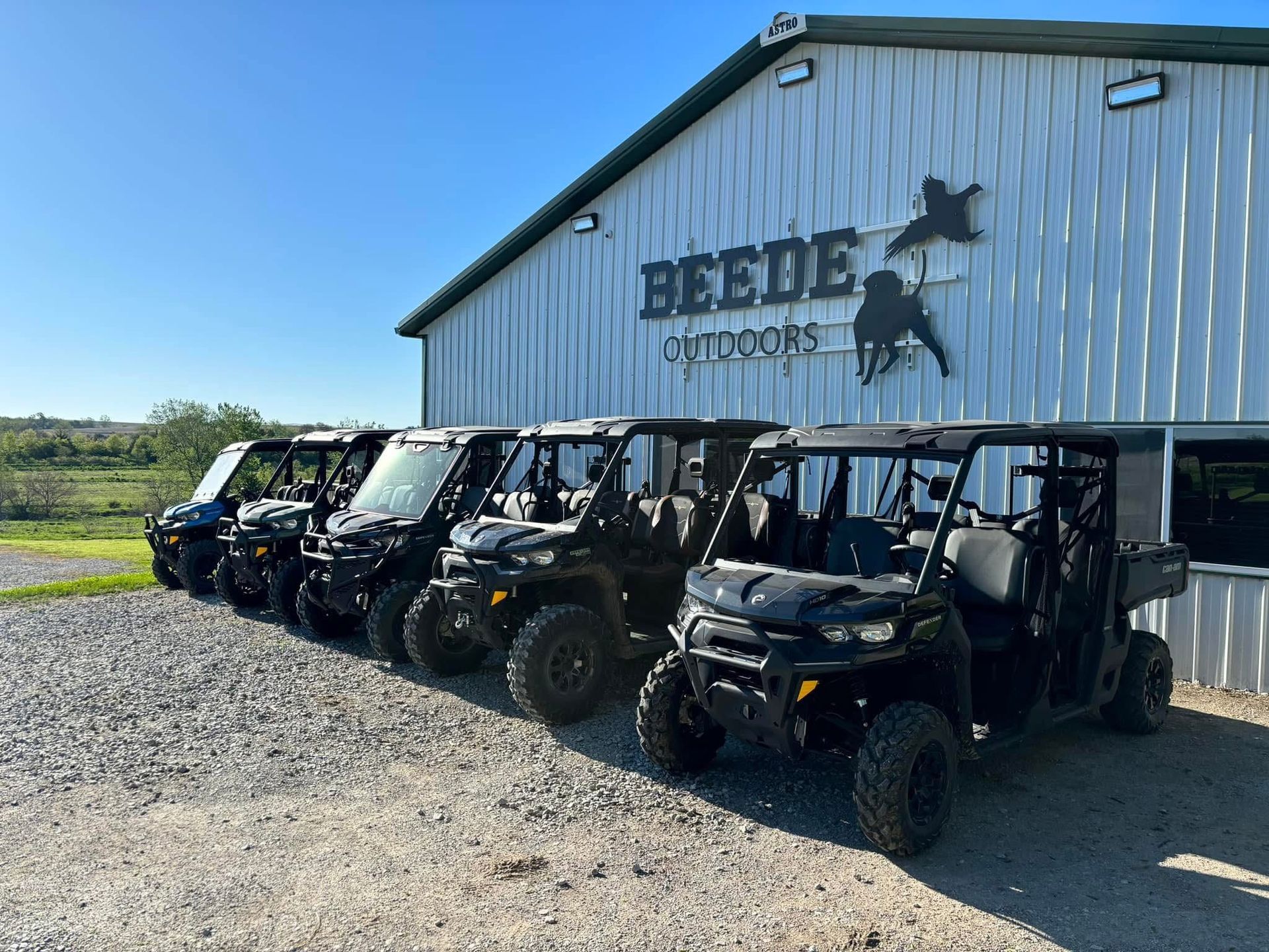 Row of black side-by-side ATVs parked outside a building with 