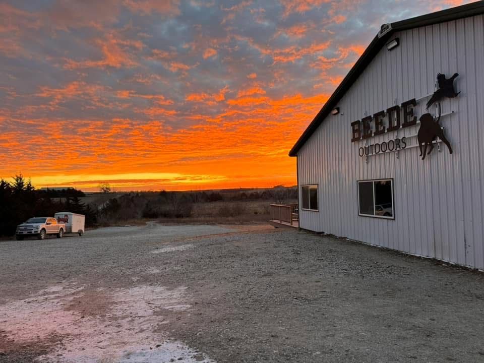 Orange sunset over a gravel lot and a white building with 