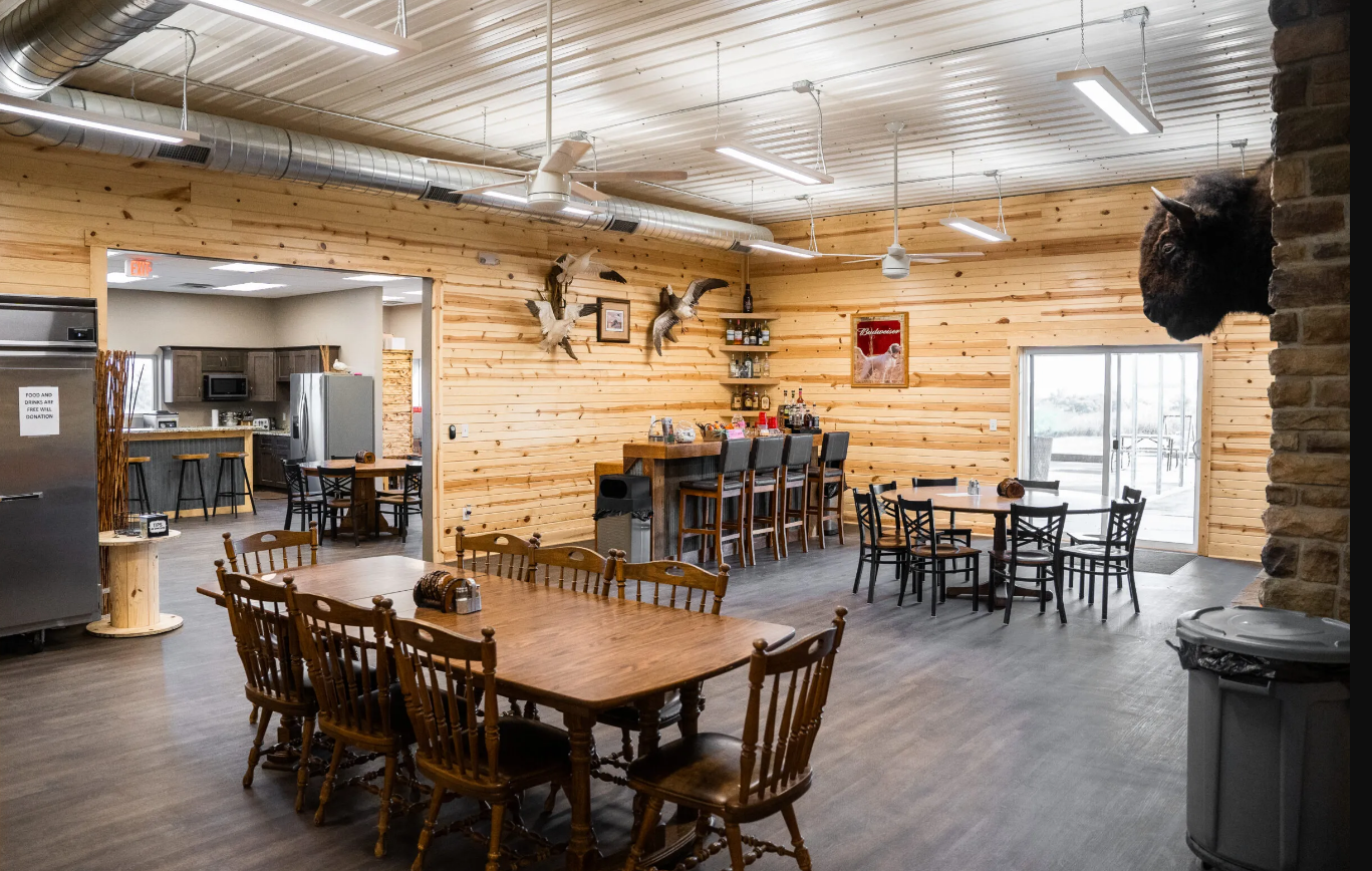 Hunting lodge interior: wooden walls, tables and chairs.