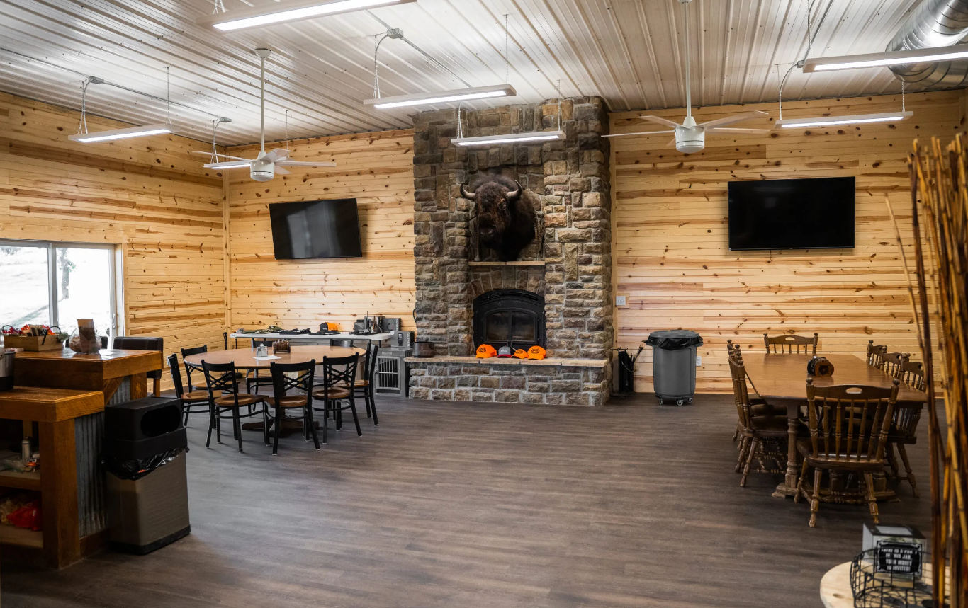 Rustic interior with fireplace, tables, TV screens, and wood paneling.