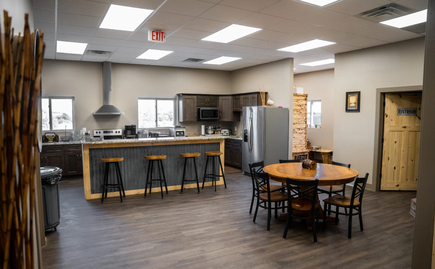 Open kitchen and dining area with bar seating, appliances, and a round table with chairs.