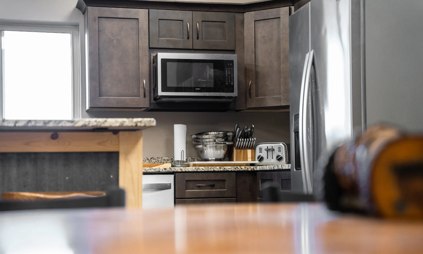 Kitchen with dark wooden cabinets, stainless steel appliances, and countertop.