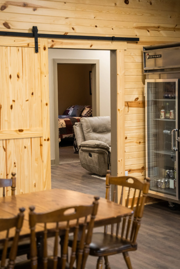 Wooden dining room with a sliding barn door leading to a bedroom with a recliner.