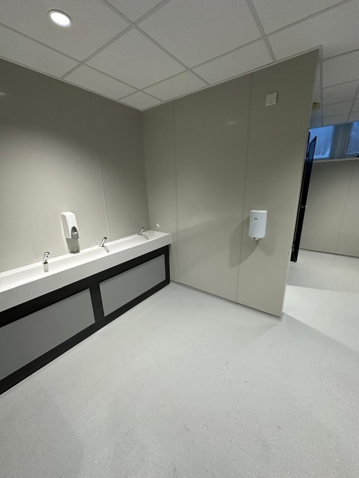 A bathroom with a sink and a soap dispenser on the wall.