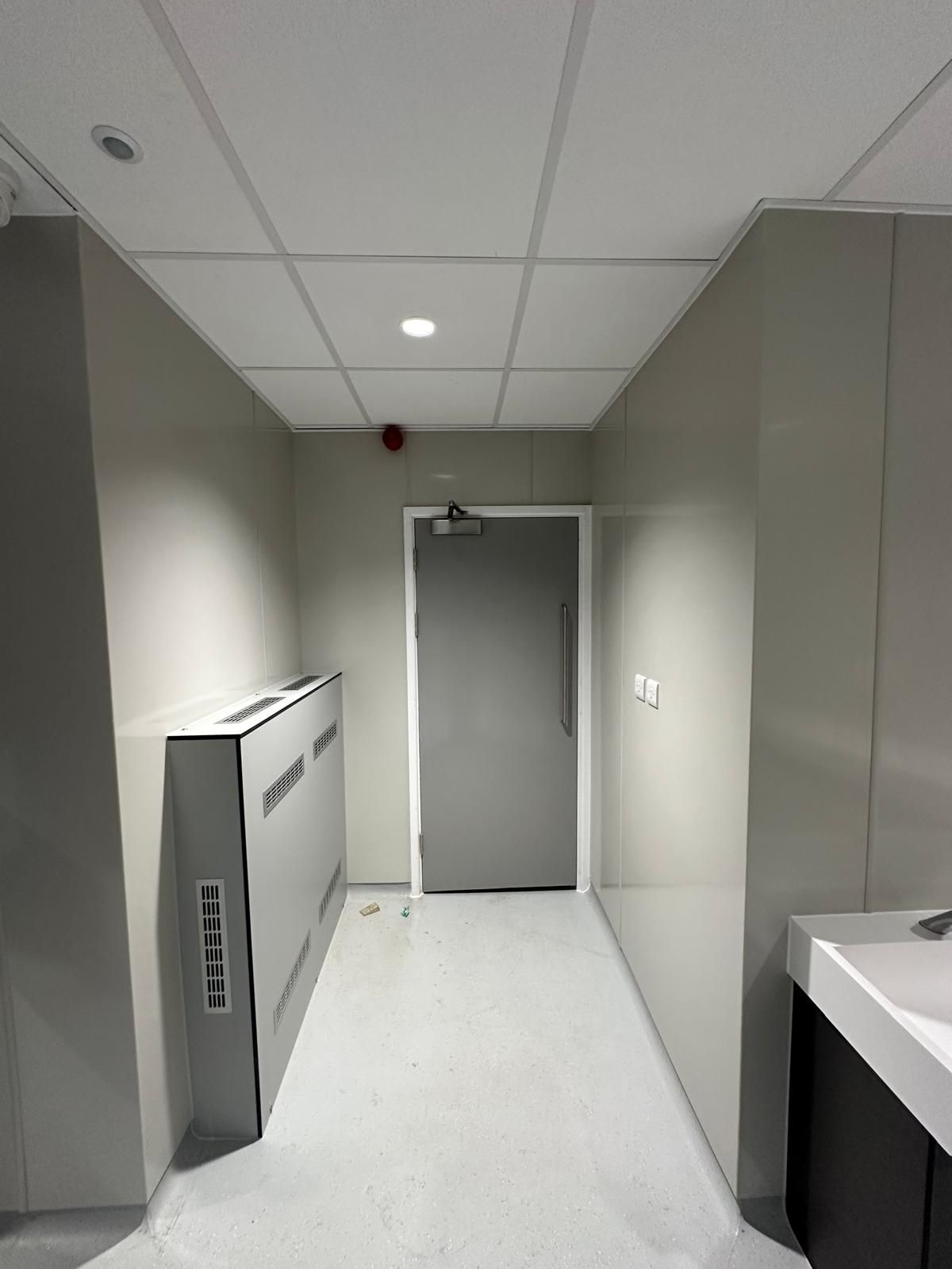 A long hallway with a door and a sink in it