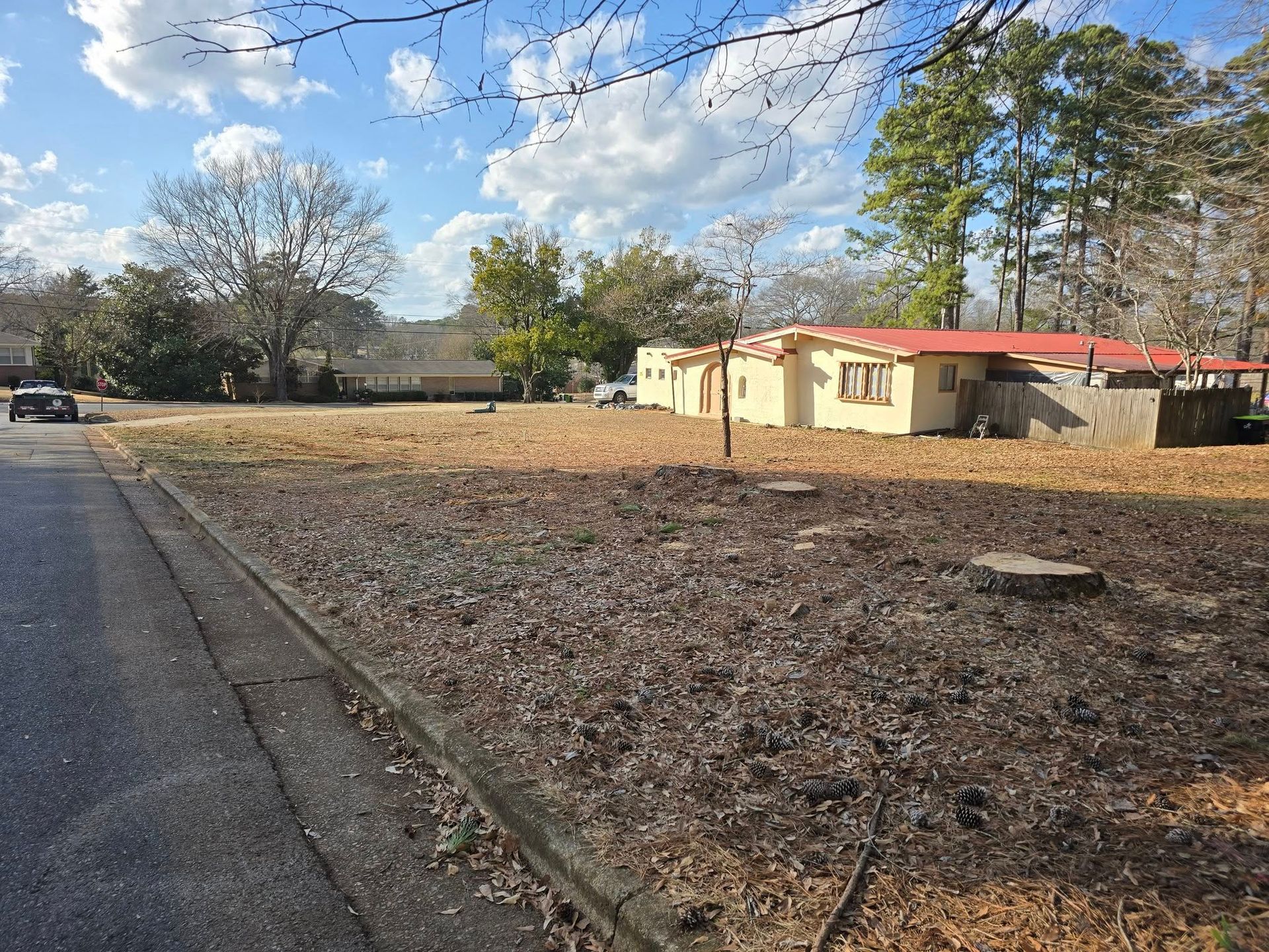 A house with a red roof is sitting in the middle of a dirt field.