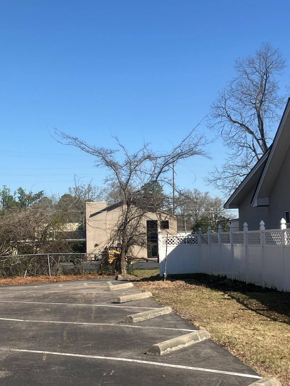 A parking lot with a white fence and a tree in the background.