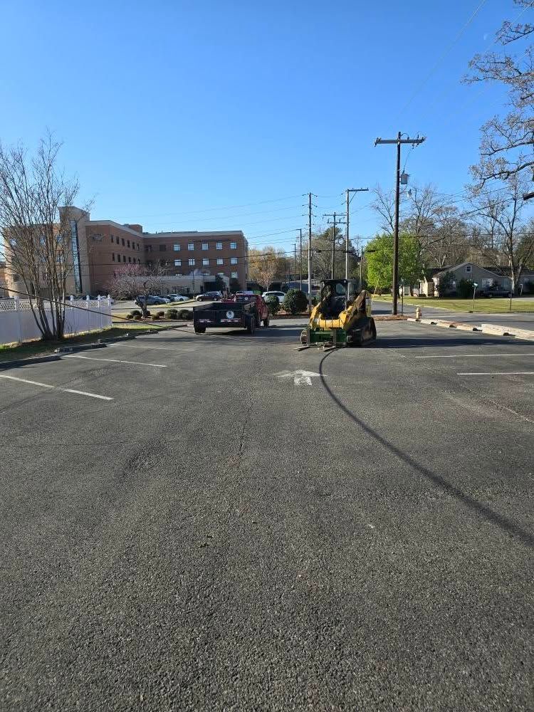 A forklift is driving down a parking lot next to a building.