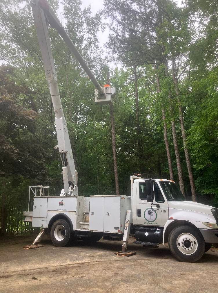 A white truck with a crane on top of it is parked in a parking lot.