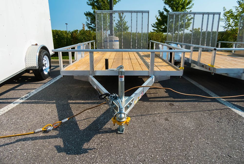 Aluminum utility trailer with wood deck, parking lot.