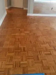 Person installing dark wood flooring, using a ruler and hammer.