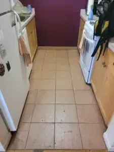 Narrow kitchen with beige tile floor, two counters, appliances on either side, and a purple wall.