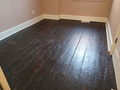 Wooden parquet flooring in a room with white baseboards and light walls.