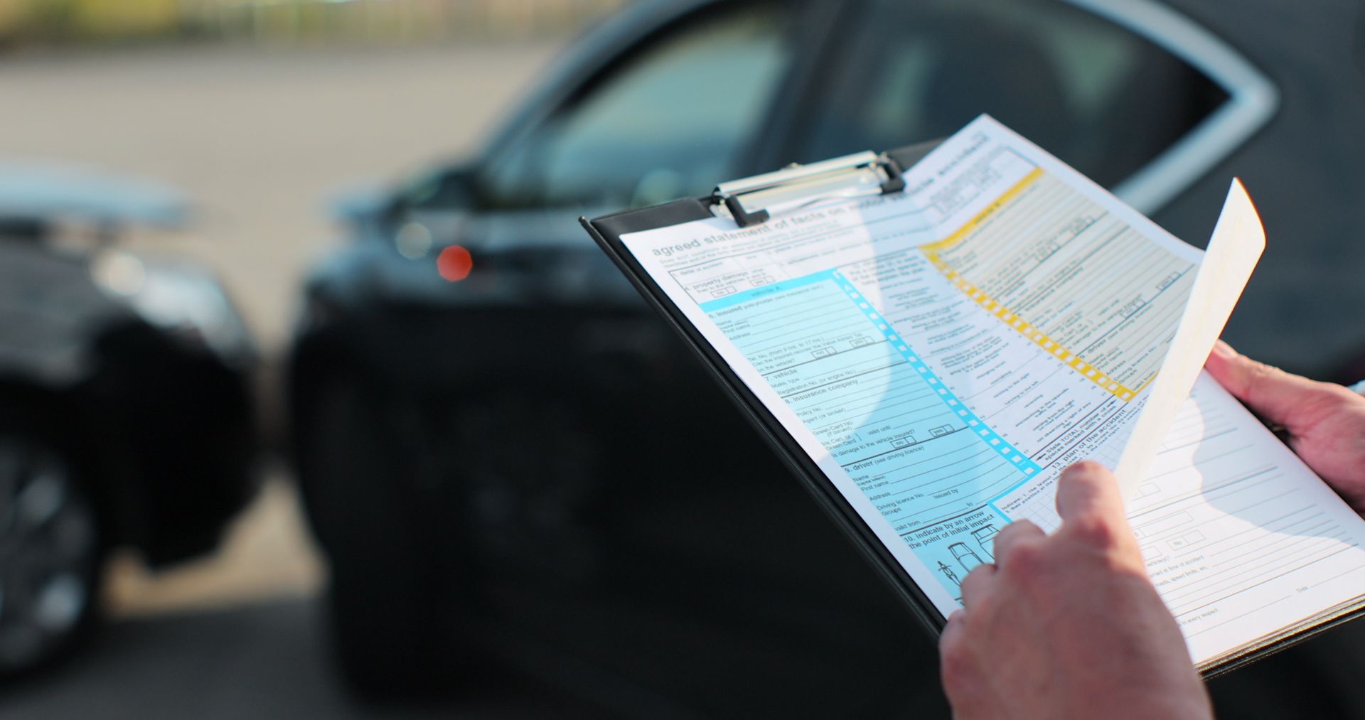 Uma pessoa está segurando uma prancheta em frente a um acidente de carro.