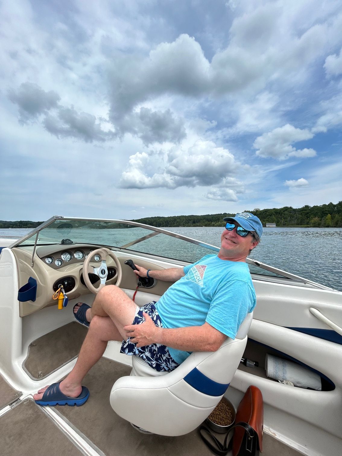 A man is sitting in the cockpit of a boat