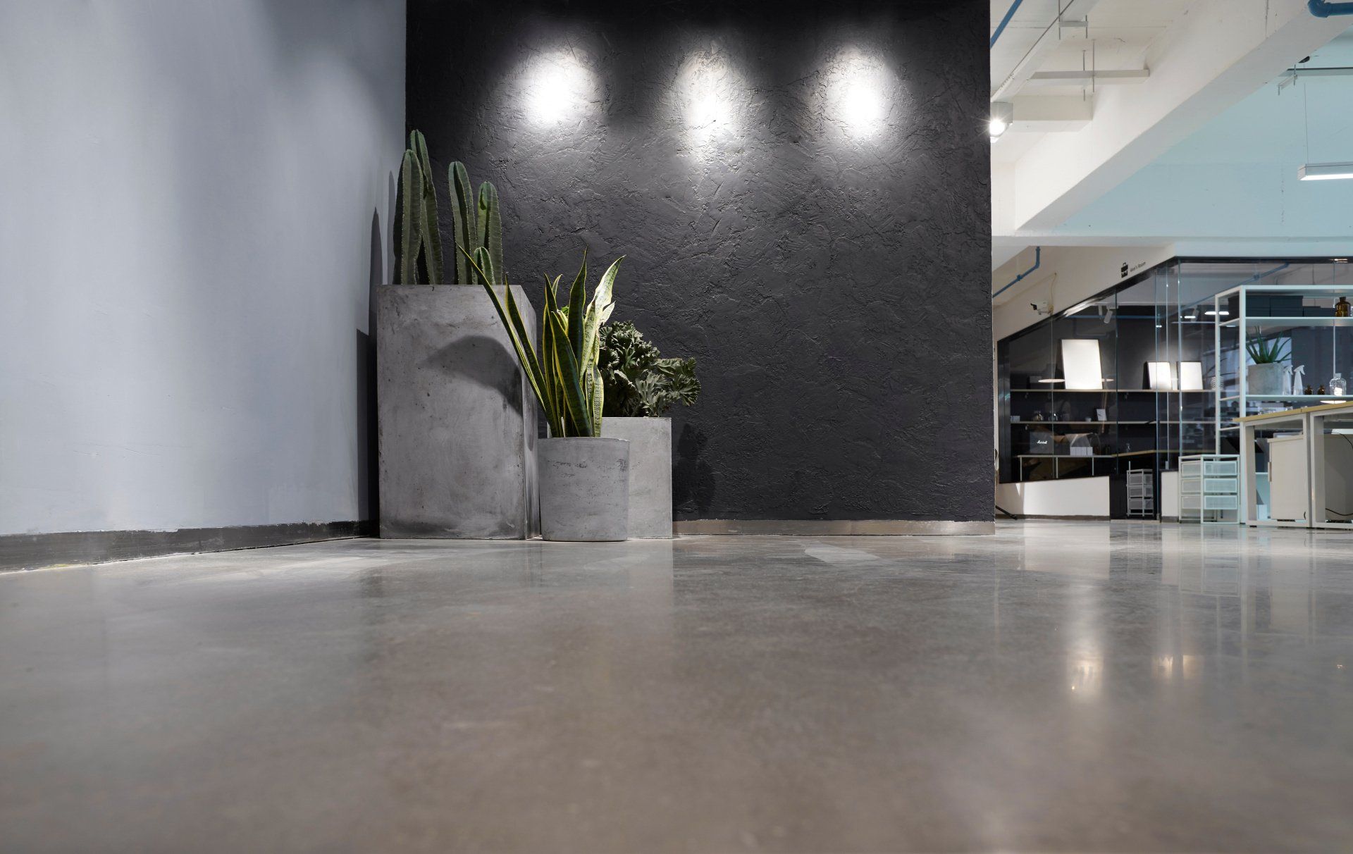 A large empty room with a concrete floor and a black wall.