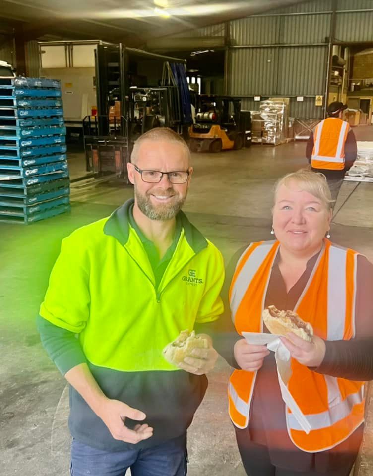 Man and a Woman Are Standing Next to Each Other in a Warehouse Eating Sandwiches — Grants Express in Sydney, NSW