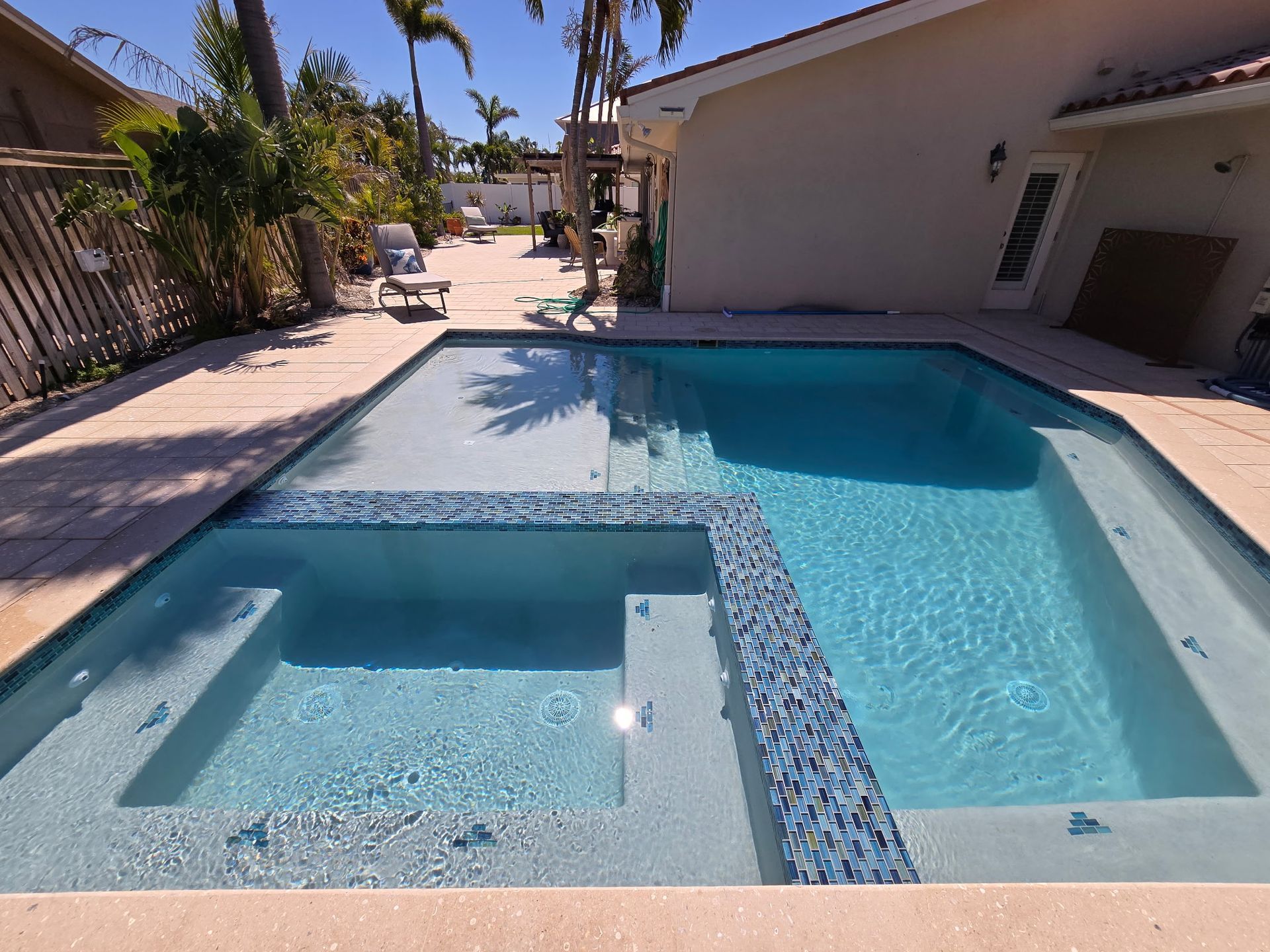 A remodeled swimming pool with an integrated hot tub.