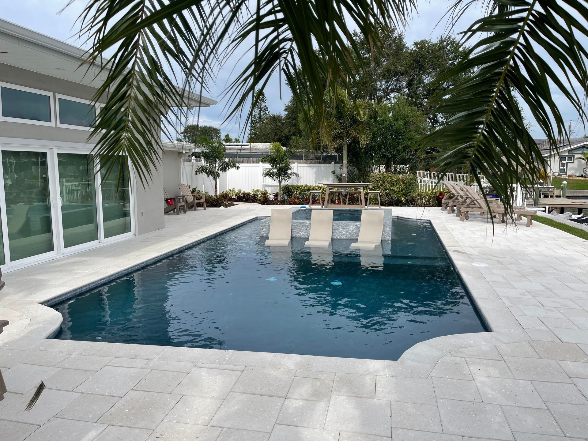 A large swimming pool is surrounded by palm trees
