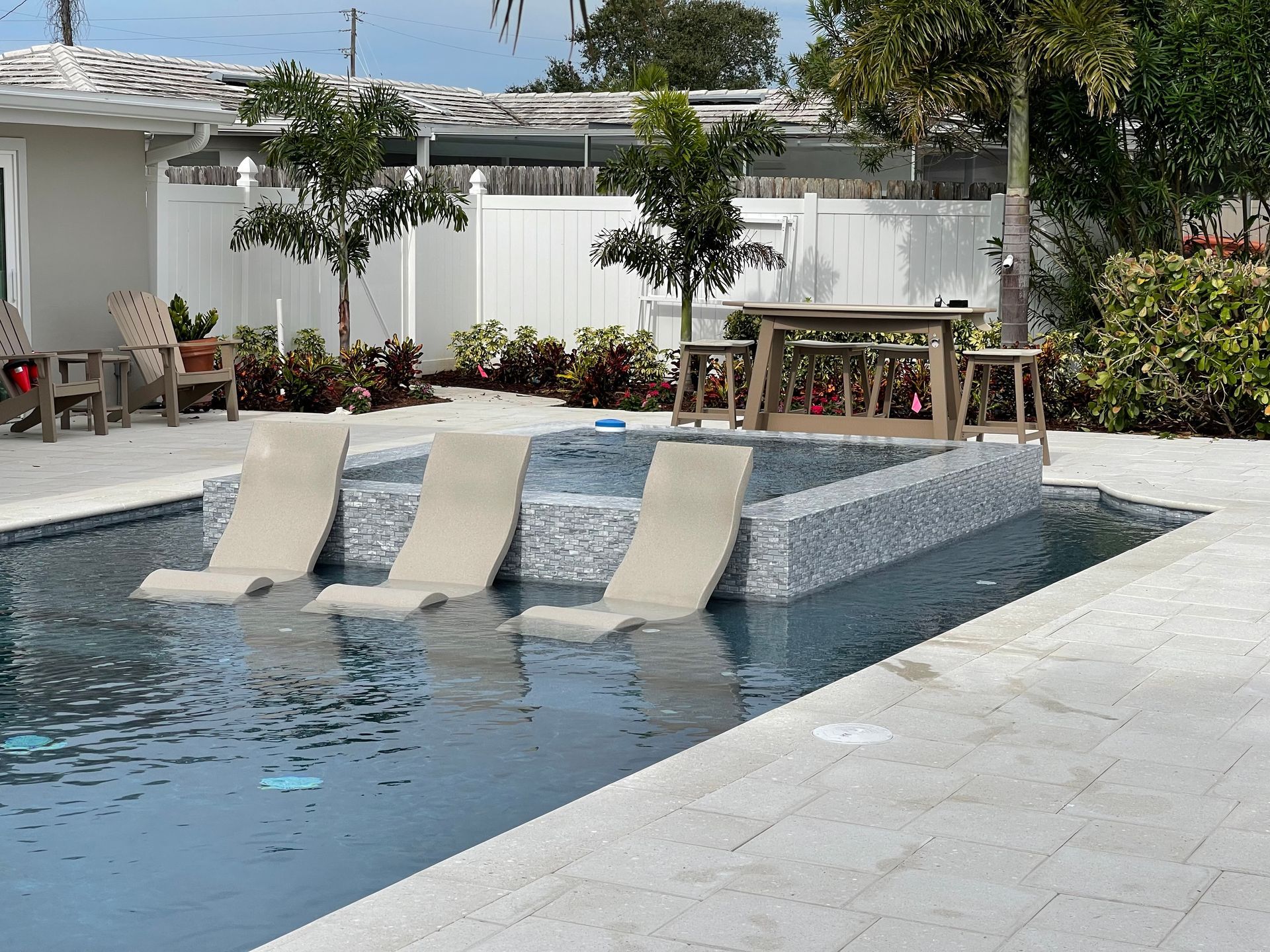 A swimming pool with a table and chairs in the background