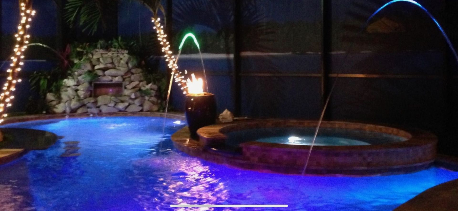 A swimming pool is lit up with blue lights at night.