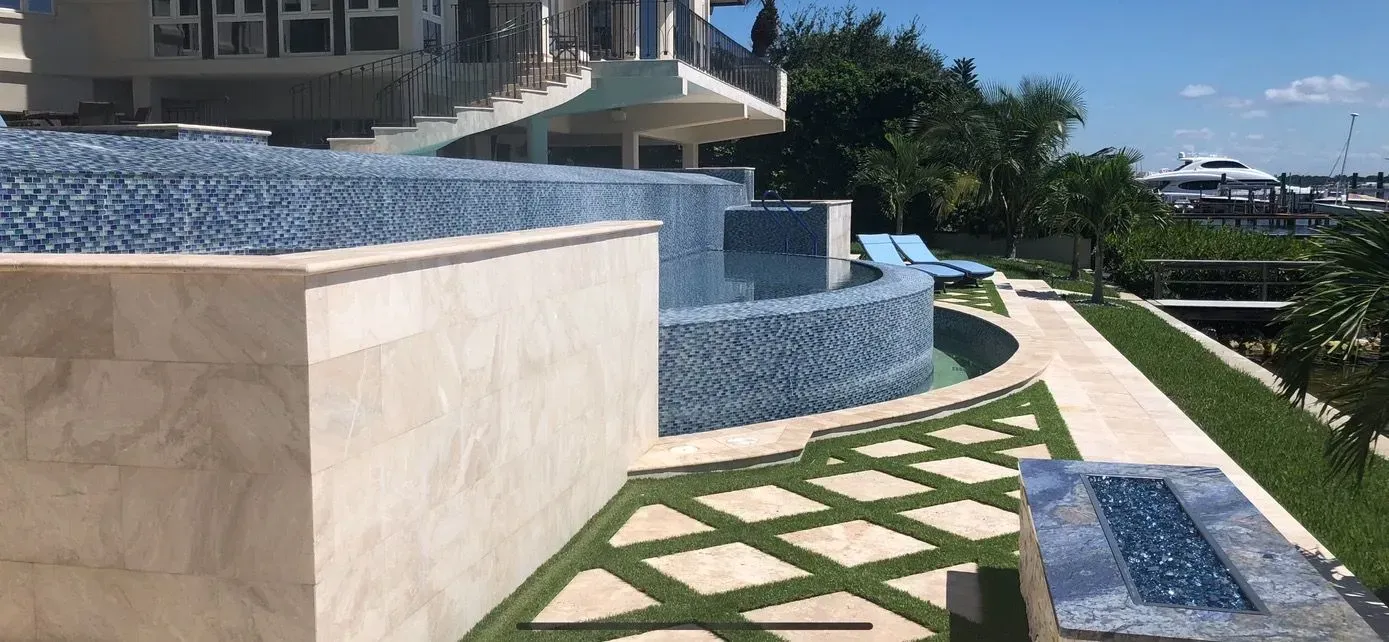 Luxurious custom pool with infinity edge beside a modern home overlooking a marina.