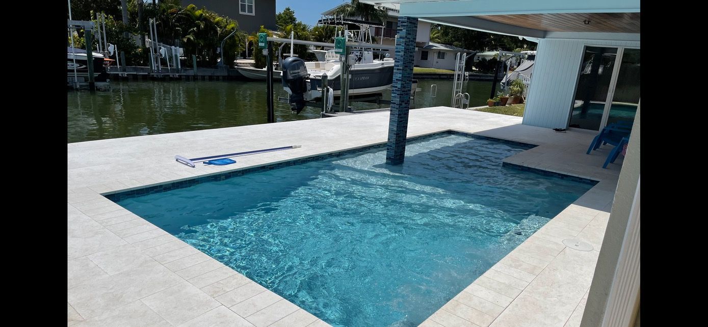 A large swimming pool is surrounded by water and a dock.